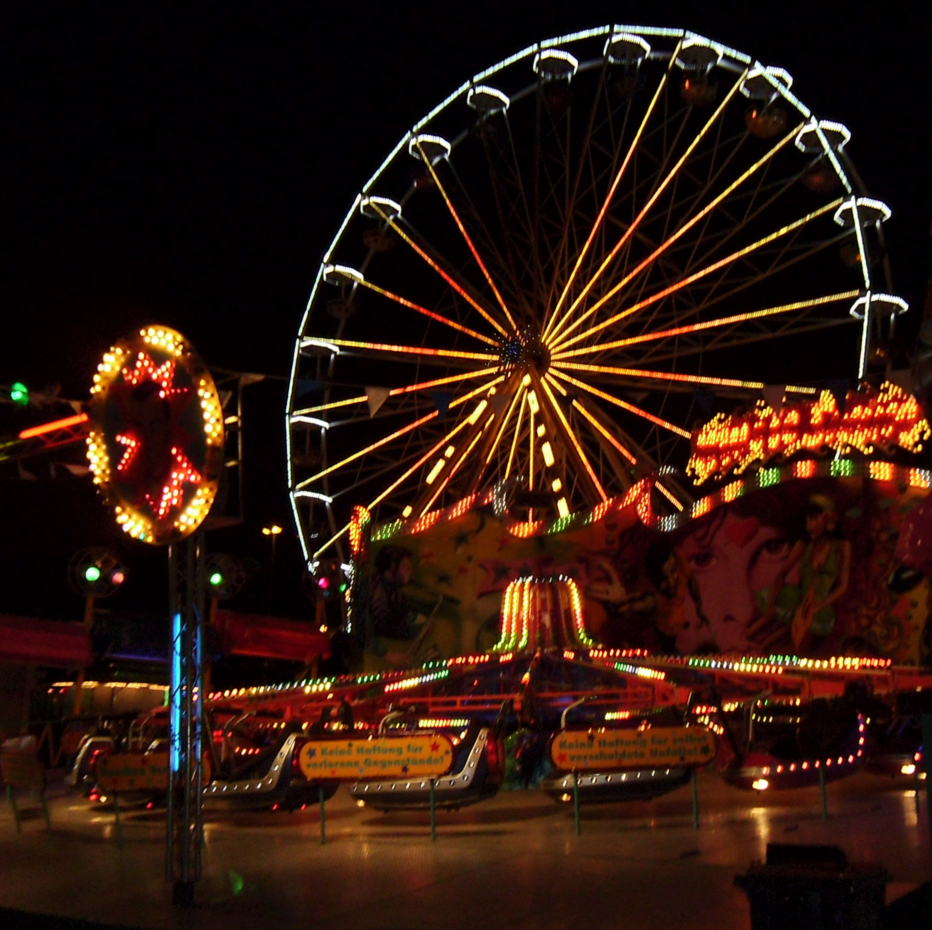 Riesenrad bei Nacht mit Karussell auf der Saarbruecker Kirmes