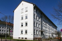 Giebel und Vorderseite Mehrfamilienhäuser mit weißer Fassade mit Satteldach, vier Etagen. Rundum Abstandsgrün.