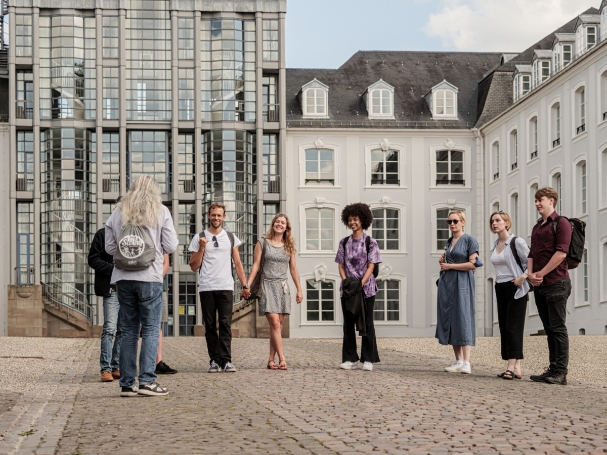 Gruppe von Touristen während einer Stadtführung vor dem Saarbrücker Schloss