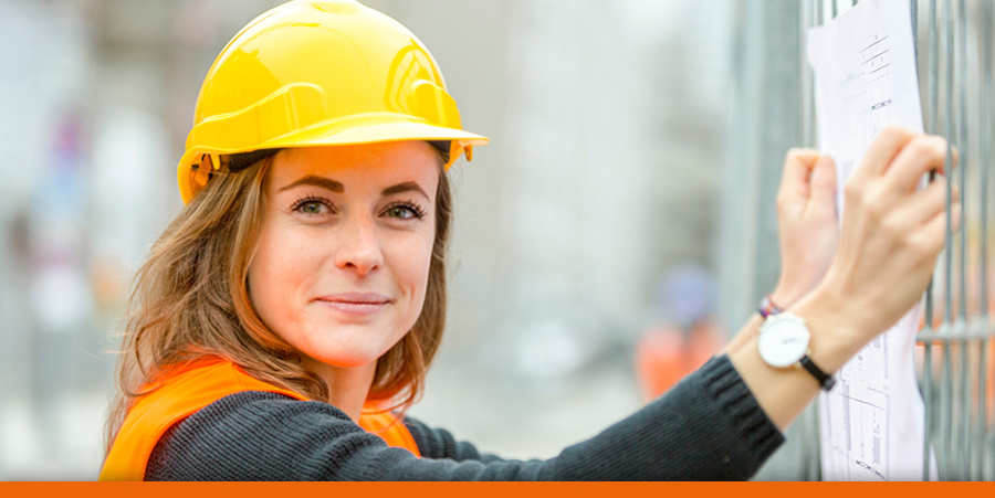 Frau mit Bauhelm auf einer Baustelle hält einen Bauplan in den Händen. Foto: cineberg, adobe stock
