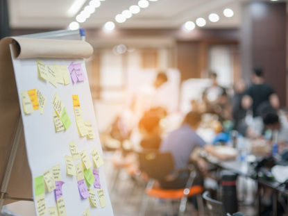 Flipchart im Vordergrund, Menschen im Hintergrund