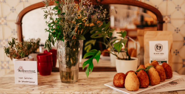 Sideboard in Lilli's Kuchenwerkstatt mit Blumenvase, zubereiteten Speisen und Kaffeebohnen 