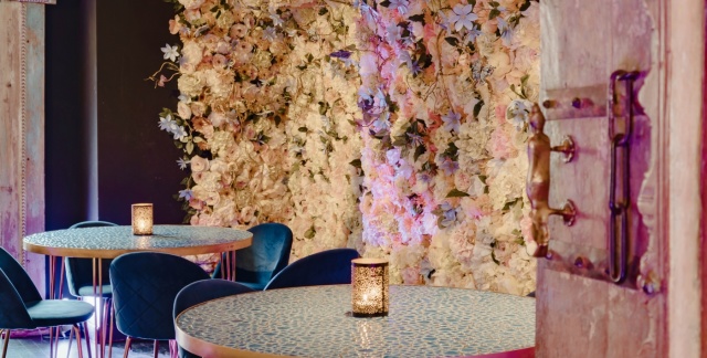 Das Innere des Lokals mit Tischen und Blumenwand im Hintergrund