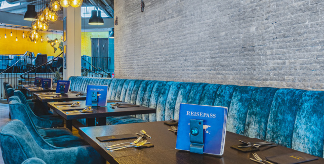 Ein Blick ins Restaurant mit blauen Samtsesseln mit Industrielampen.