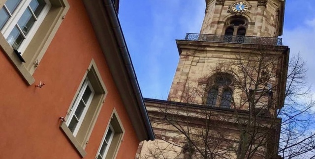 Gebäude mit Aufschrift Thonet im Vordergrund und der Basilika Sankt Johann im Hintergrund