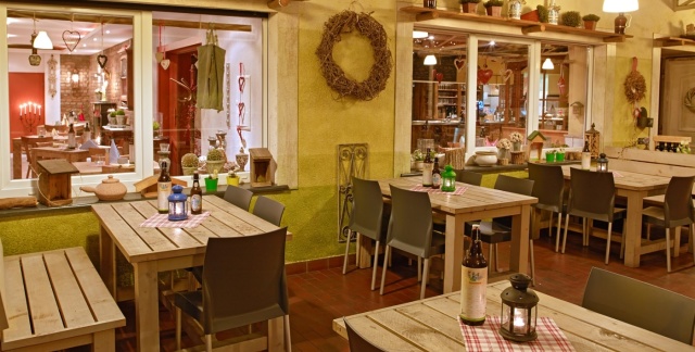 Raum mit dekorierten Holztischen und grüner Wand