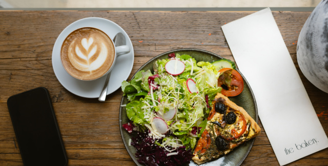 Tasse Kaffee und Teller mit Salat und Brokkoli-Quiche