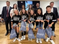 Jungendtanzgruppe steht in Trikots mit ihren Erinnerungsgeschenken vorne. Dahinter stehen Erwachsene, wie der Oberbürgermeister und weitere, wohlmöglich Trainer