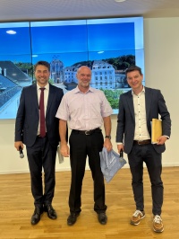 Links der OB, in der Mitte ein Mann mit Urkunde, rechts der Amtsleiter