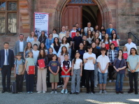 Eine Gruppe von Schülern und Erwachsenen steht auf der Treppe eines alten Gebäudes