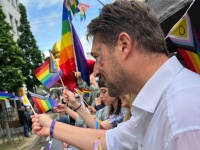 Ein Mann winkt von einem Veranstaltungswagen beim CSD den Besuchern zu