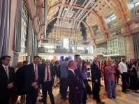 Menschen in Anzügen stehen in einem sehr großen Festsaal