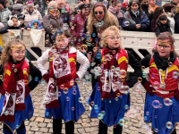 Vier junge Tänzerinnen in rot-blauen Kostümen stehen zwischen schwebenden Seifenblasen vor dem Publikum.